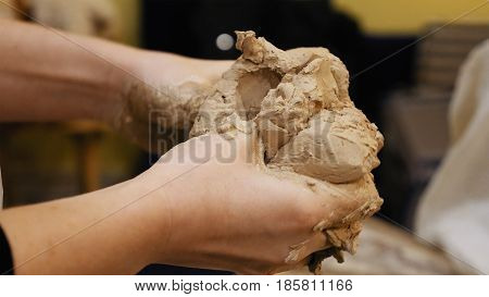 Female sculptor is pugging and kneading clay for creating pottery ceramics. Art and handicraft modelling creation.