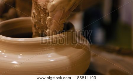 Potter is making clay pot bowl or vase ceramics porcelain on the potter's wheel. Creating pottery art and handicraft modelling creation.