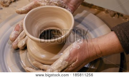 Potter is making clay pot bowl or vase ceramics porcelain on the potter's wheel. Creating pottery art and handicraft modelling creation.