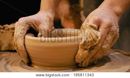 Potter is making clay pot bowl or vase ceramics porcelain on the potter's wheel. Creating pottery art and handicraft modelling creation.