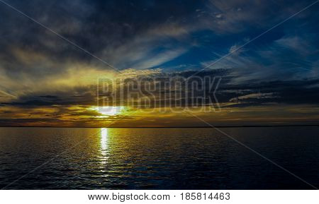 Beautiful sunset with clouds, light rays over the river with reflections