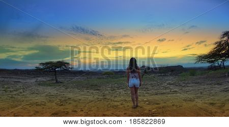 Lonely woman back watching the sunset in the Desierto de la Tatacoa (Tatacoa Desert) in Villavieja, Huila / Colombia