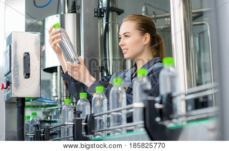 Female worker at a water bottling factory near conveyor