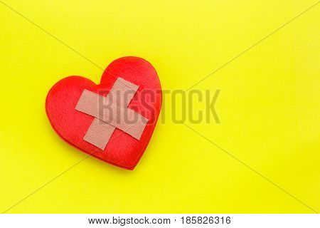 Plaster Or Band-aid On Red Heart Shape On Yellow Background. Use For Heart Problem Or Illness Concep