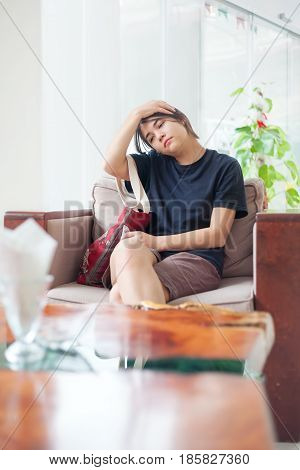 Biracial teen girl sitting in hotel lobby with neckache