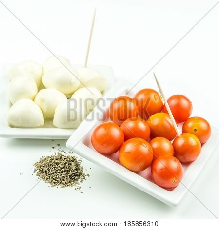 cherry tomatos mozarella and ground basil with toothpicks on white background