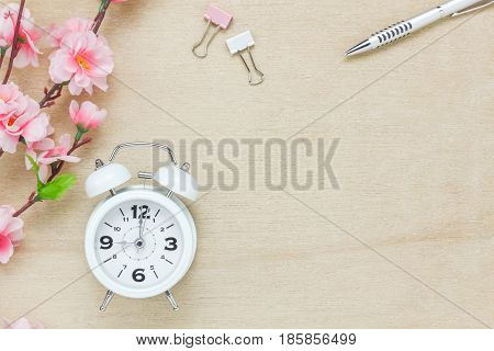 Top view business office desk background.The silver pen coffee beautiful pink flower wood white clock on wooden table backgtound with copy space.