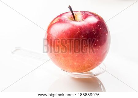 red apple on translucent medicine spoon on the table symbolising that drinking and eating of apple products prevents diseases and is full of vitamins