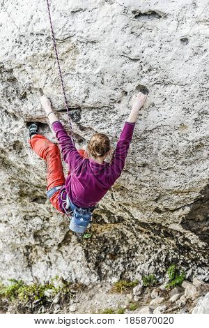 Podlesice Poland april 30 2017: Young female climber climbing a route on a rock. Jura krakowsko chestochowska.