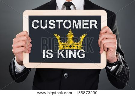Close-up Of A Man Showing A Slate With Customer Is King Written On It