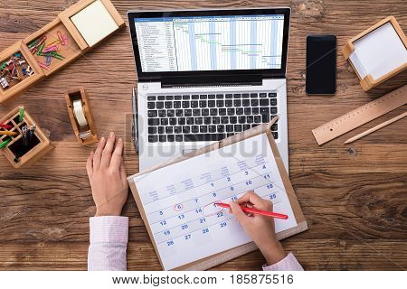 Businesswoman Marking A Date On Calendar At Workplace