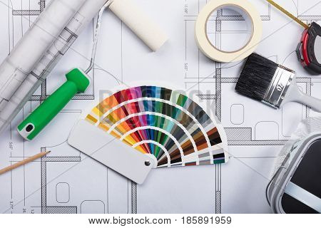 High Angle View Of Color Guide Swatch On Blueprints With Paint Roller And Paint Brush