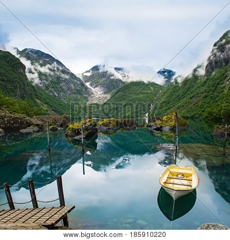 Fishing boat on a still lake in Norway and high mountains in background. Bondhusvatnet