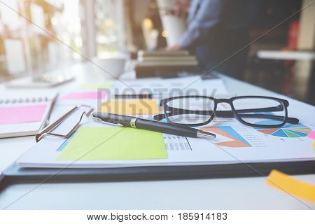 Business concept with copy space. Office desk table with pen focus and analysis chart computer notebook cup of coffee on desk.Vintage tone Retro filter effect.Selective focus.