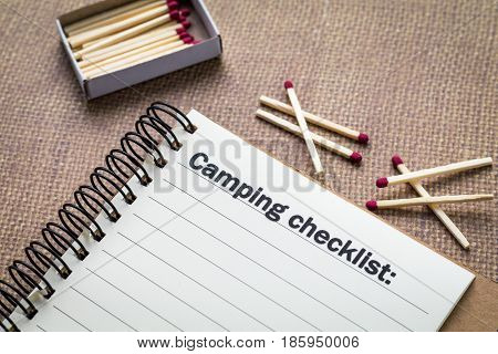 Camping checklist concept on notebook with match box and wooden matches
