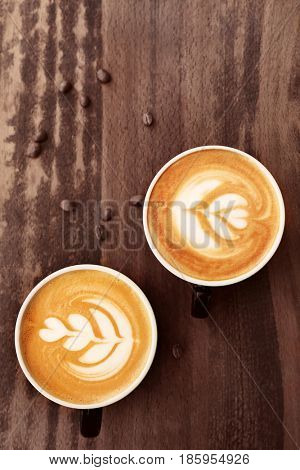 Cups of coffee with latte art on wooden background