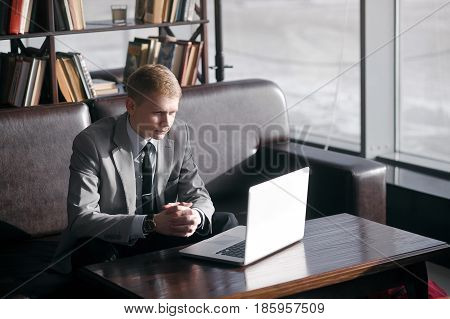 young businesswoman working at a laptop sitting at the table. looks at the notebook and folded his hands on the table.