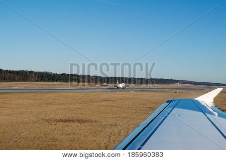 NUREMBERG, GERMANY - JAN 20th, 2017: Aircraft window view of the Nuremberg airport apron, Air Berlin Airbus A320 is landing in the background.