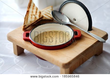 Delicious soup puree of mushrooms in iron pots with toasts of white bread
