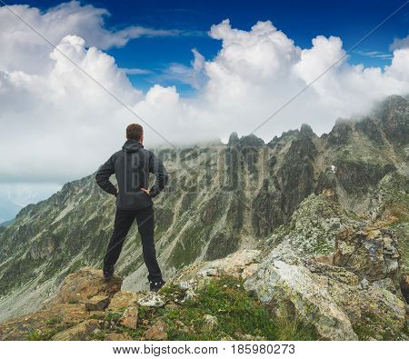 Hiker stays on a rocky ridge and enjoy blue sky above the mountain valley. Caucasian Georgia Swaneti region.
