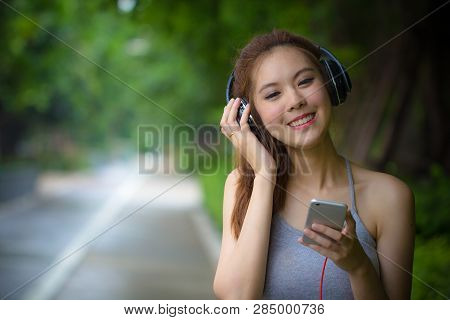 Happy Young Woman Using Smartphone Relaxing And Singing While Listening Music With Earphones. Asian 