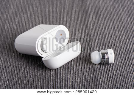 Wireless Cordless Bluetooth Earbuds With Chargeable Case On A Fabric Background