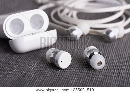 Wireless Cordless Bluetooth Earbuds With Chargeable Case On A Background Of Cable Earphone