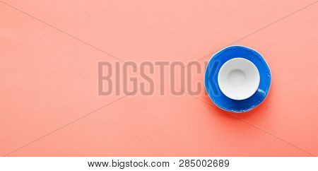 Blue Coffee Cup And Sauser On Trendy Coral Background Table, Top View, Copy Space, Selective Focus