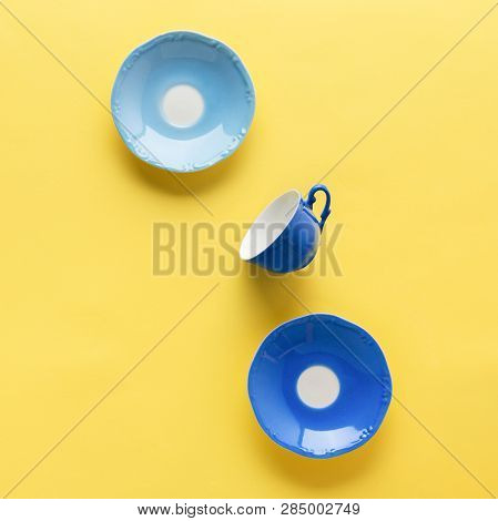Blue Coffee Cup And Sausers On Yellow Background Table, Top View, Copy Space, Selective Focus