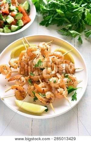 Shrimp Skewers. Grilled Prawns Skewers With Greens, Spices And Lemon On White Plate Over Wooden Tabl