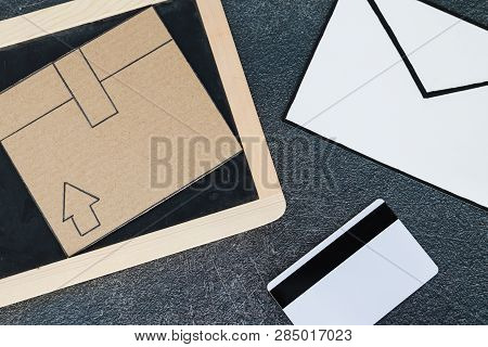 Cardboard Parcel With Blackboard Email Envelope And Payment Card On Concrete Desk, Concept Of Shippi