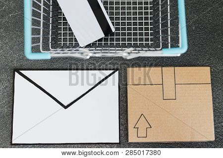 Shopping Cart With Cardboard Parcel Email Envelope And Payment Card On Concrete Desk, Concept Of Shi