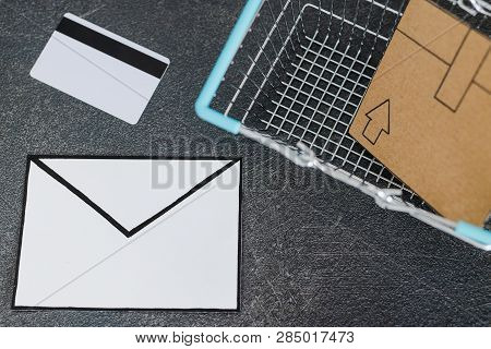 Shopping Cart With Cardboard Parcel Email Envelope And Payment Card On Concrete Desk, Concept Of Shi