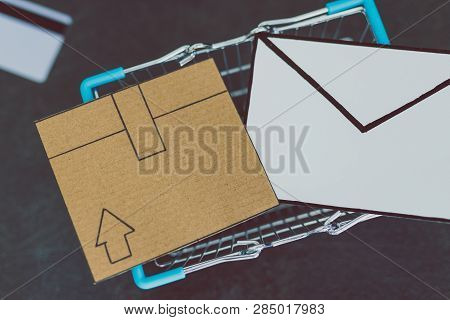 Shopping Cart With Cardboard Parcel Email Envelope And Payment Card On Concrete Desk, Concept Of Shi