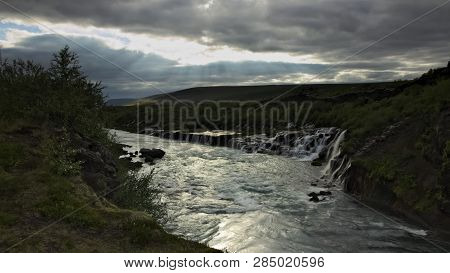 Longer Exposure Of Hraunfossar Waterfall On Hvita River With Overcast Sky With Some Sunlight Coming 
