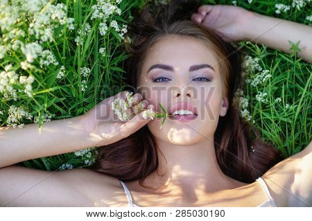 Closeup  face of young woman with clean skin. Skin care. Beautiful girl is on nature on green grass.  Portrait of a pretty  model. Caucasian woman is relaxing and enjoying with summer time. 