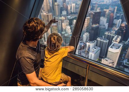 Dad And Son Are Looking At Kuala Lumpur Cityscape. Panoramic View Of Kuala Lumpur City Skyline Eveni