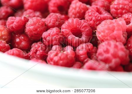 Ripe raspberry in the mug. Fresh raspberry on white background. Juicy red berries on the table. Delicious and healthy food. A healthy way of life. Sweet raspberry. Jam of raspberries. Summer berry