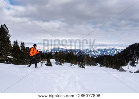 Man In Orange Jacket Snowshoeing On Scheibelalm In Holiday Resort Hohentauern With Panoramic View To