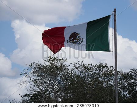 National Maxican Flag At Chichen Itza City Near Fantastic Archaeological Site In Mexico With Trees A
