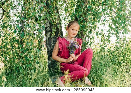 Summer Portrait Of Cute Little Girl Holding Small Bouquet Of Wild Flowers