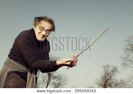 Man In Ugly Style Dress Practicing In Dowsing With Rods
