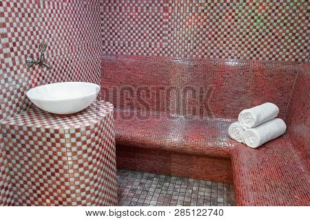 Traditional Turkish Hamam With Stone Walls, Sink And Stack Of  Towels