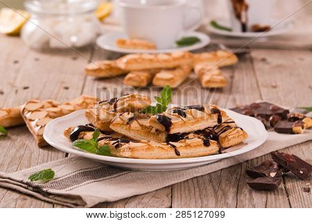 Puff Pastry Cookies With Chocolate Icing On White Dish.