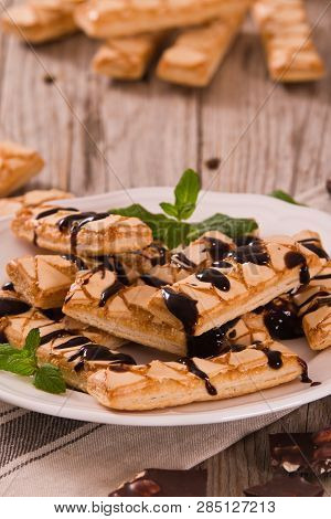 Puff Pastry Cookies With Chocolate Icing On White Dish.