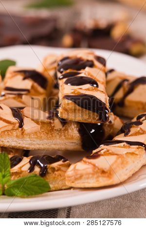Puff Pastry Cookies With Chocolate Icing On White Dish.