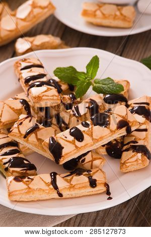 Puff Pastry Cookies With Chocolate Icing On White Dish.