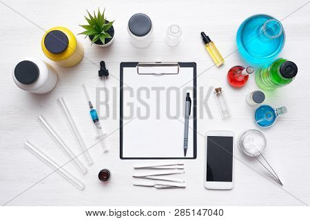 Laboratory Table With A Blank Paper Sheet Of Researching Results, Mobile Phone And A Chemical Reagen