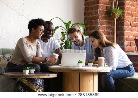 Diverse Friends Sitting In Cafe Watching Funny Videos Using Computer