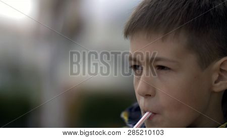 Boy Drinks A Milkshake At A Cafe Outdoors
